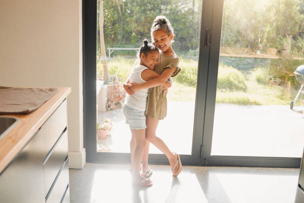 istock Two happy mixed race sisters wearing casual clothes while having fun together at home. Children only being affectionate while bonding and playing in a kitchen against bright copyspace 1403452566