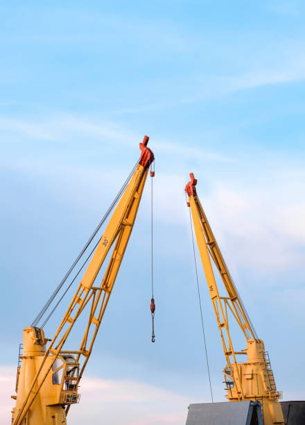 istock Two yellow cranes on nautical vessel at harbor against cloudy sky background 1403454073