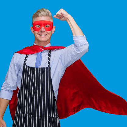 Front view of with blond hair male hero standing in front of blue background wearing costume who is successful and cheering and showing fist who is and doing fist pump