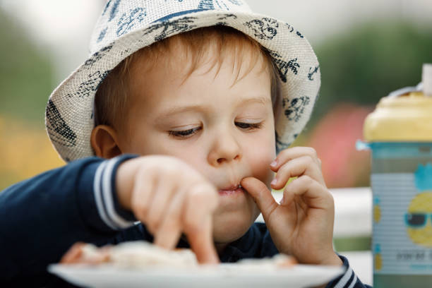 istock Little boy eating toasted bread for breakfast on colour garden background. 1403454314
