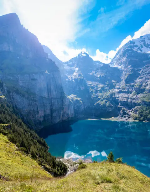 View from above the lake in summer weather. The famous Oeschinensee lake which is located at 1500 meters above sea level and is located above Kandersteg in the Bernese Oberland, Canton of Bern, Switzerland