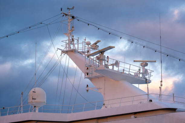 gros plan d’un mât radar de navire contre des nuages d’orage sombres au coucher du soleil - sea safety antenna radar photos et images de collection