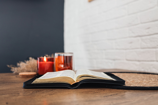 Open Holy Bible on a old wooden table and white wall background. Religion concept. Cozy warm photo