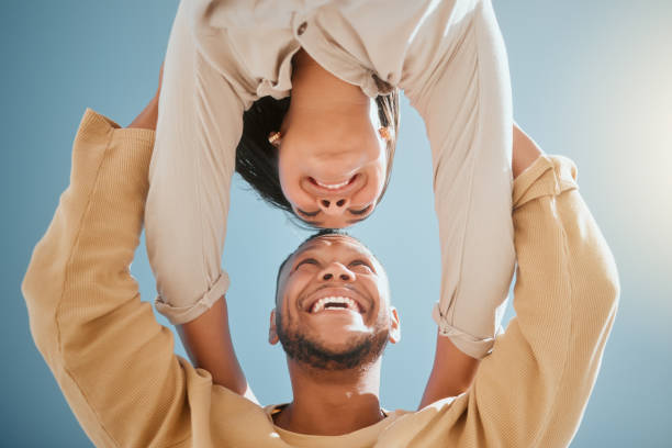 istock Happy young mixed race couple facing each other while standing with their hands on each others shoulders and smiling against a blue sky, from below 1403460983