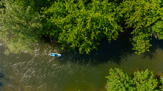 Photo of a young man paddleboarding on the river