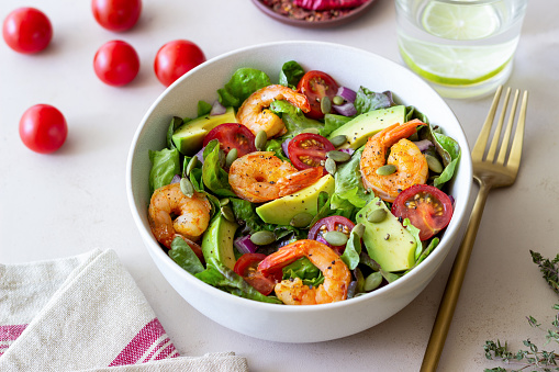 Salad with shrimps, avocado, tomatoes, onions and seeds. Healthy eating.