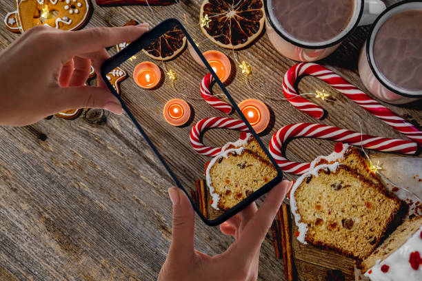 Festive gingerbread figures near candles and candies on wooden table with copy space, top view. Phone shooting for blog