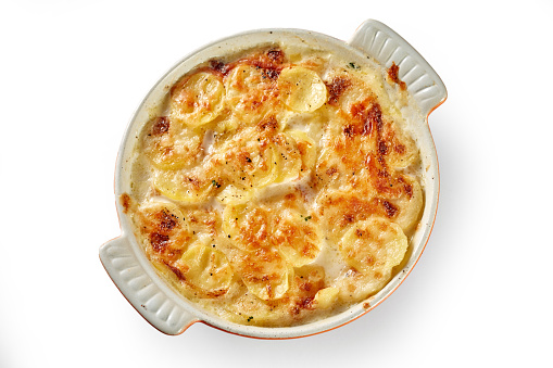 Top view of palatable gratin made of potatoes and cheese in casserole and served on white isolated background