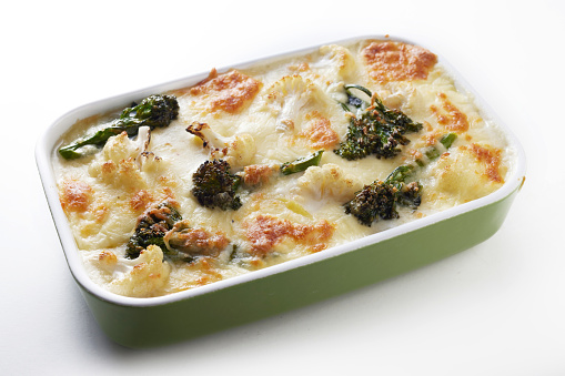 From above of yummy gratin with broccoli and cauliflower baked in ceramic casserole pan with cheese and cream and served on white background