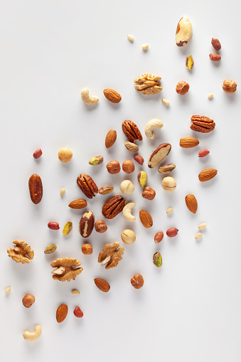 Сlose-up of nuts on a white background: pistachios, walnuts, hazelnuts, macadamia, almonds, pecans, pine nuts, brazil nuts, peanuts and cashews