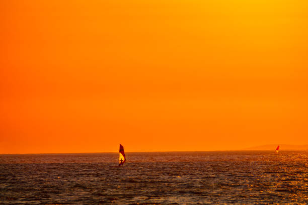 シルエット 燃えたオレンジ色の夏の夜の空が波に乗るウィンドサーファーの上に広がる - kiteboarding sunlight croatia dalmatia ストックフォトと画像