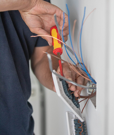 Electrician tradesman carrying out the final wiring of a residential property - connecting light switches