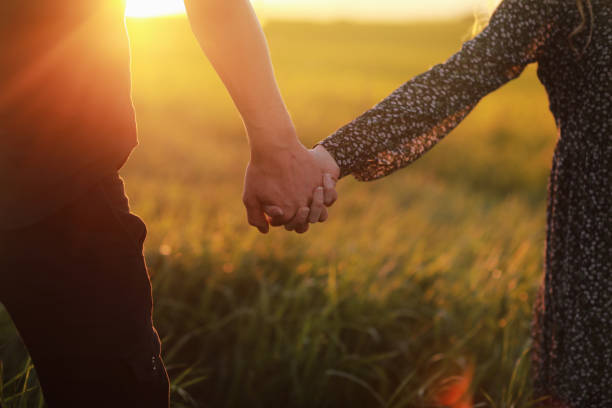 istock Couple hold hands in green field on sunset 1403471529