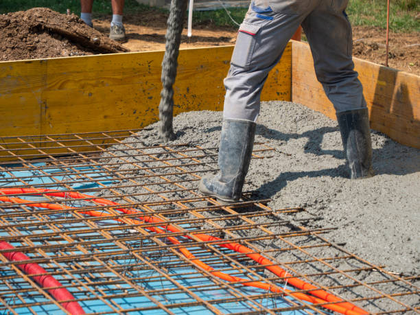 istock CLOSE UP: Builders are pouring cement mixture and leveling a house foundation. 1403472084