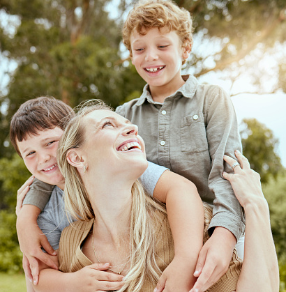 A happy caucasian single parent enjoying playing with her sons in the backyard. Smiling family of three having fun in a garden outside