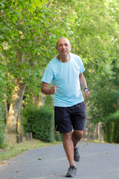 istock Bald older man running through the park and doing sports to get in shape and slim his belly 1403473403