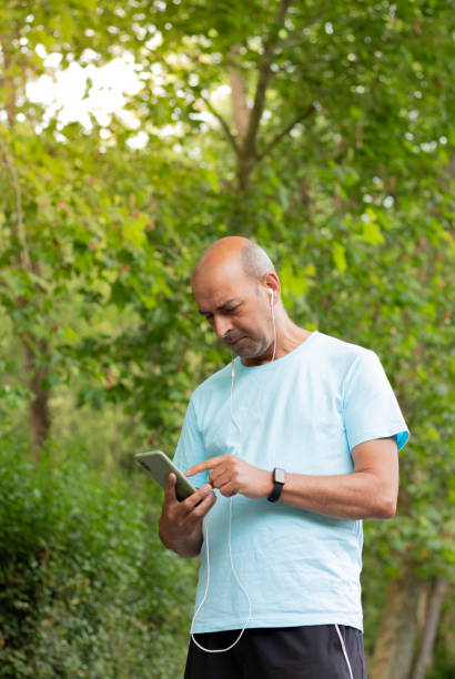 istock Man in sportswear and hairless walking through nature and consulting the route on his mobile phone 1403473448