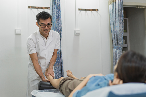 Traditional Chinese Medicine Therapy - A Chinese physician treats a walk in female patient with massage therapy