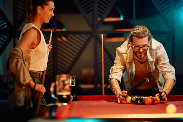 istock Happy man arranging pool balls in triangle while playing billiard with his girlfriend in a pub. 1403475187