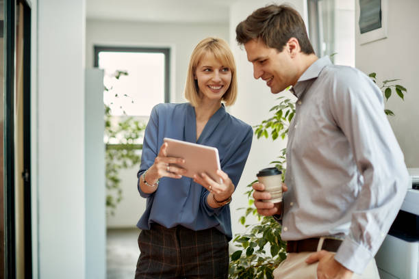 istock Happy business colleagues using touchpad on coffee break in a hallway. 1403475761