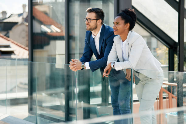 Happy multiracial entrepreneurs enjoying the view from office balcony.