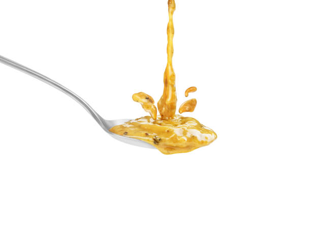 istock yellow sauce with herbs in a spoon on a white background 1403478010