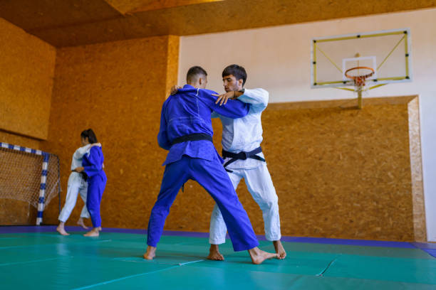 istock Two young couples of judo martial arts partners practicing new techniques in a gym 1403478617