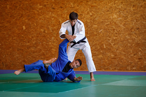 Two young male judo fighters showing technical skill while practicing martial arts in a fight club