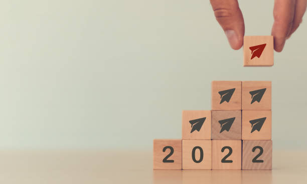 istock Business concept in 2022 for new ideas creativity and innovative solution and new opportunity concept. Man putting red paper plane symbol on wooden cube standing with other black on white background. 1403478861