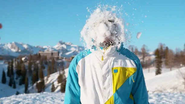 Photo of CLOSE UP: Cheerful Caucasian guy snowboarding in Slovenia gets hit by a snowball