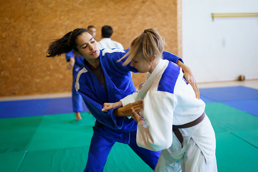 Two young couples of judo martial arts partners practicing new techniques in a gym