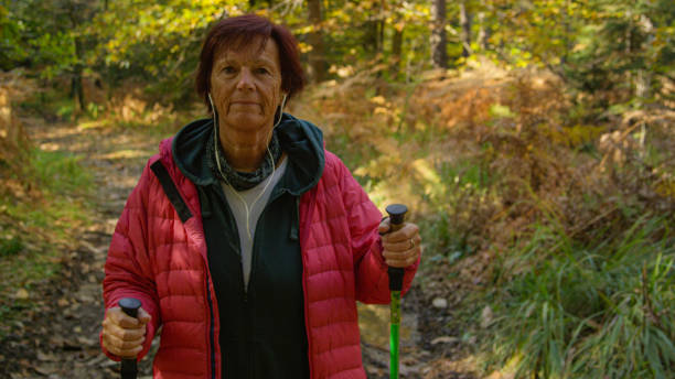 istock PORTRAIT: Smiling retiree unwinds by listening to podcast and exploring forest. 1403480454
