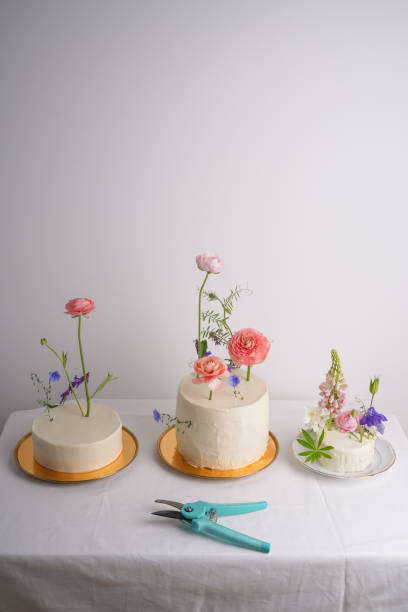 istock Three white cakes  on a white table with a gadget for cutting flowers 1403484622