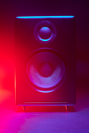 Close up of black audio speaker with red and blue color gradient led lights