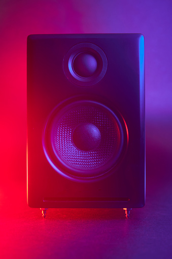 Close up of black audio speaker with red and blue color gradient led lights