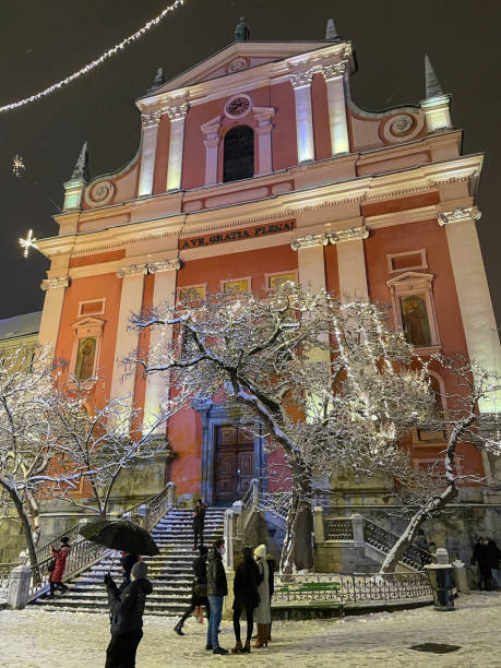 vertikal: kirchtürme über touristen, die festliche straßen von ljubljana erkunden. - ljubljana december winter christmas stock-fotos und bilder