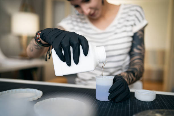 istock Craft woman pouring epoxy in the cup, while working from her home workshop 1403486280