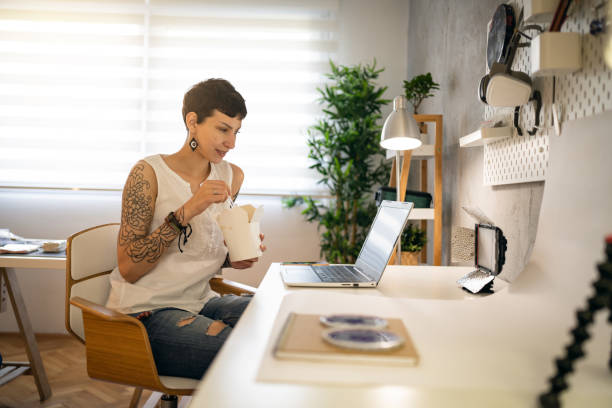 istock Female small business owner, working on laptop while having a meal 1403487356