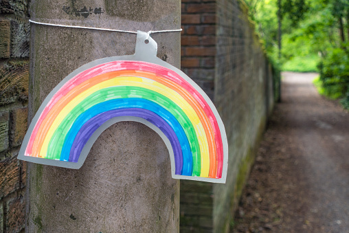 A small rainbow, drawn on paper and tied to a lamppost, representing hope.