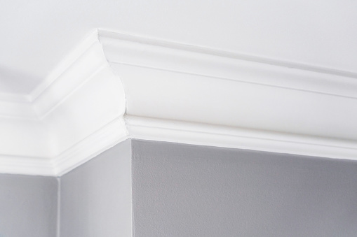 Close-up of a simple white painted cornice, joining the wall of an interior room with the ceiling.