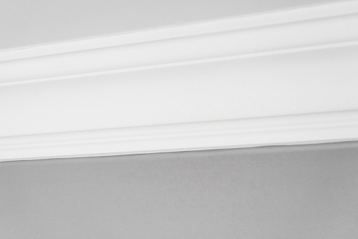 A simple white cornice in a living room, joining the wall to the ceiling.