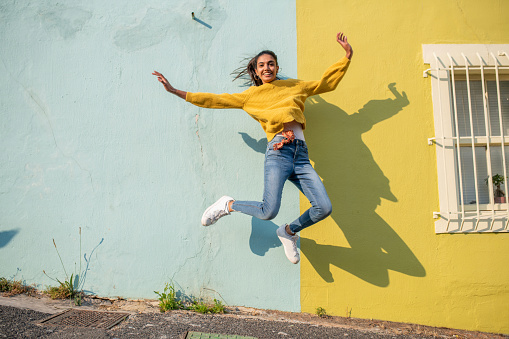Young Indian woman jumping.She has light blue wall as a background