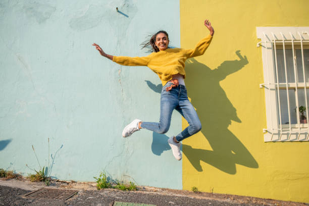 Jump! Young Indian woman jumping.She has light blue wall as a background excited woman yellow stock pictures, royalty-free photos & images