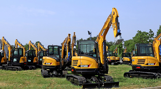 Pradamano, Italy. June 5, 2022. Brand new Sany excavators in a row on the grass outside the official dealer of the chinese heavy machineries manufacturer.