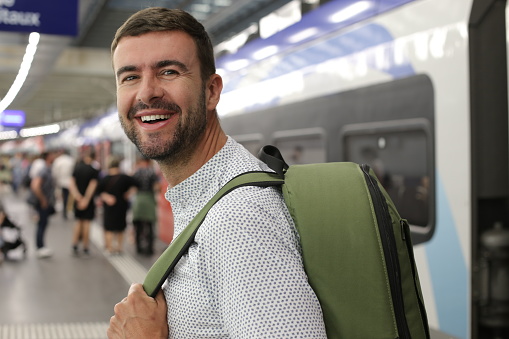 A 40 years old Caucasian entrepreneur is taking a train while holding a green backpack .