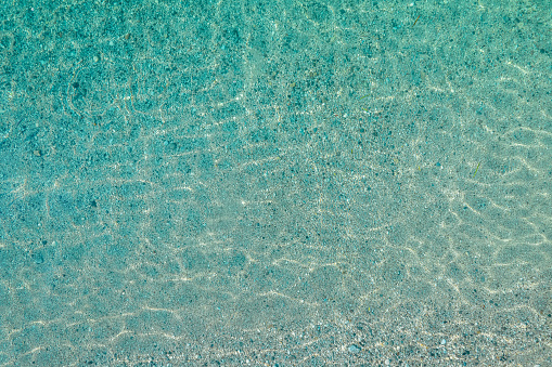 Blue, turquoise transparent water surface of ocean, sea, lagoon. Horizontal background. Top view of sand beach. Aerial, drone view