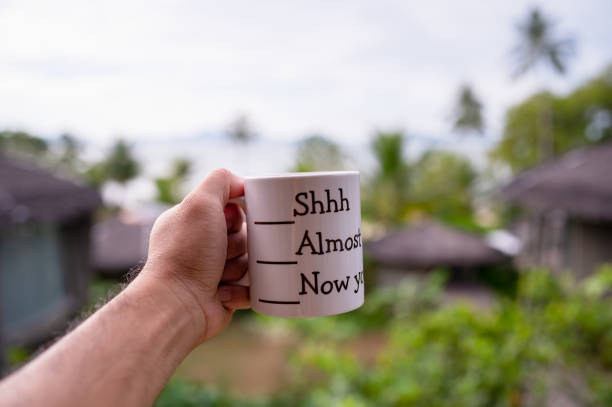 istock Man hand holding a white coffee cup on green background. Sea view, sky, drink concept. 1403506897