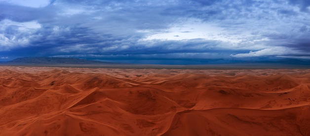 Aerial panorama view on sand dunes with storm clouds at sunset in Gobi Desert, Mongolia