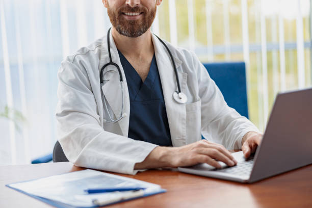 istock Close up of healthcare worker with stethoscope using laptop while working at doctor's office 1403508163