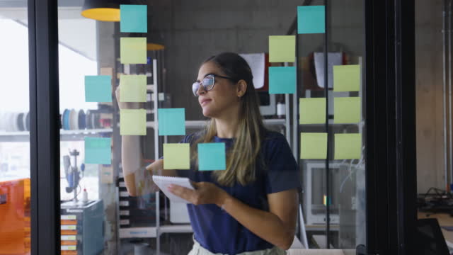 Latin American business woman brainstorming at a creative office using adhesive notes to organize her ideas